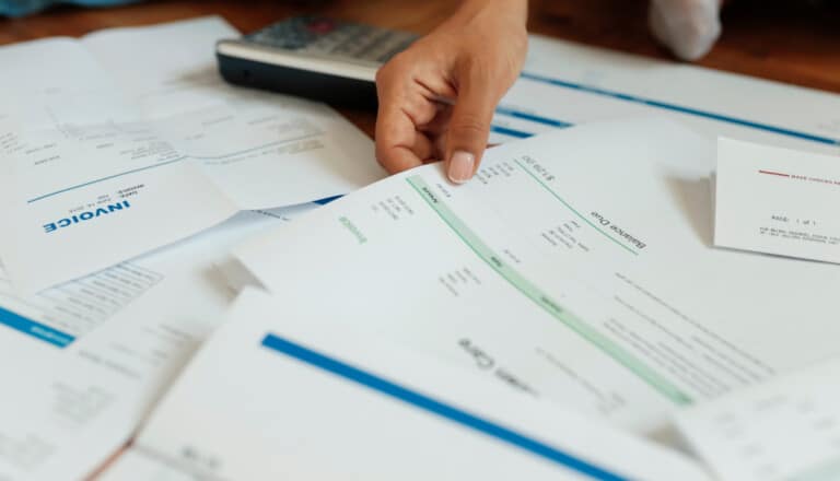 This is a photo of a person looking at bills and income statements. | Debt-to-income ratio